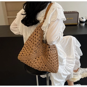 Detail of hand-woven straw tote bag with geometric hollow patterns and leather straps