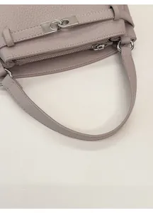 Detail of wide handle and silver lock on lavender lychee pattern leather handbag