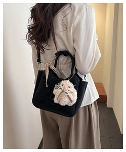Close-up of black suede bucket bag with格子纹 ribbon and pink plush bunny charm detail