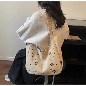 Detail shot of khaki canvas tote bag featuring cute cat and bear embroidery for women