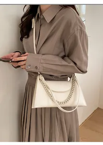 Detail of cream white leather underarm bag with gold chain strap and pebble texture
