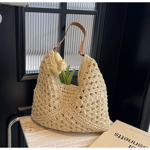 Close-up of beige hollow woven straw texture and premium brown leather shoulder strap