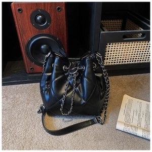 Detail of black quilted leather bucket bag featuring silver chain drawstring and hardware