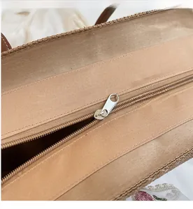 Vue détaillée de la fermeture éclair argentée sur le sac cabas en paille tressée kaki