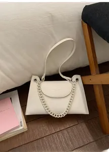 Detail of white trapezoid shoulder bag with lychee texture and bold acrylic chain