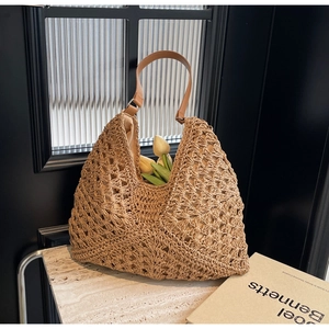 Detail of woven straw tote bag with brown leather strap and hollow crochet texture