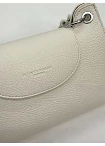 Macro shot of cream lychee pattern leather handbag with silver ring and embossed logo