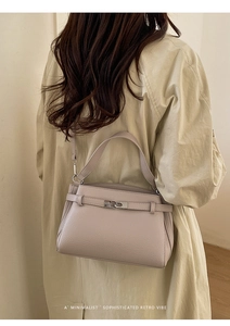 Rear view of model wearing a minimalist beige lychee pattern crossbody handbag over a trench coat