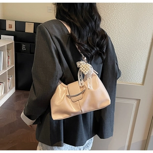 Close-up of apricot shoulder bag with silver metal bar and heart pearl lace pendant