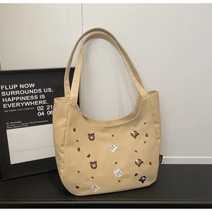 Detailed close-up of khaki canvas tote bag featuring cute animal embroidery patterns