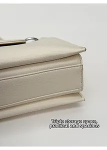 Detail view of the cream crossbody bag featuring triple internal storage compartments