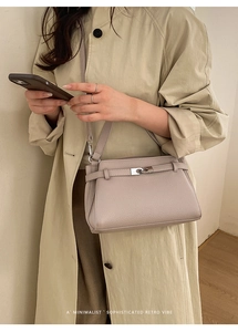 Detail of mauve lychee grain leather crossbody bag with silver buckle on beige trench coat