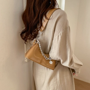 Detail of caramel brown faux leather shoulder bag featuring bold silver chain and strap