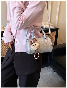 Details der silbernen Boston Bag mit Teddybären-Anhänger und Perlenkette am Modell