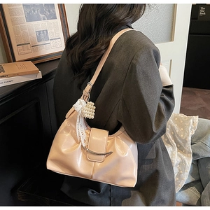 Detail of light pink patent leather shoulder bag with ruched design and pearl heart charm