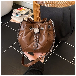 Detail of dark brown quilted leather bucket bag with silver chain strap and drawstring closure
