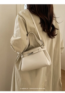 Side view of beige lychee leather handbag featuring metallic buckle and straps