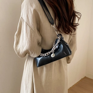 Black leather crescent bag with silver chain detail worn by model on shoulder