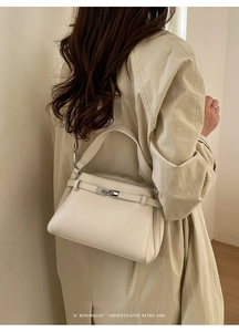 Detail of off-white lychee grain leather handbag with metal turn-lock and vintage strap