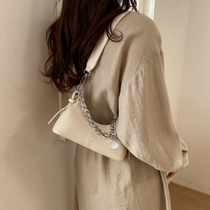 Detail of cream PU leather shoulder bag featuring silver chain and round charm