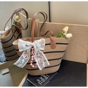 Détail du sac cabas en paille avec nœud en dentelle florale, perles roses et anses en cuir