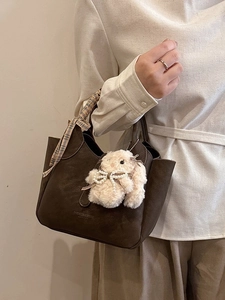 Dark brown leather bucket bag with plaid ribbon handle and white plush rabbit charm