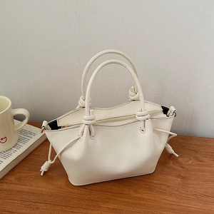 Detail of the white leather handbag featuring a knotted handle and drawstring design