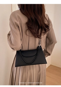Close-up of black lychee texture leather bag with thick chain and embossed logo