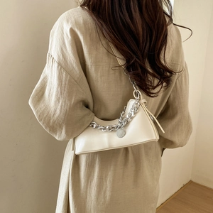 Detail of a beige half-moon shoulder bag with a silver chain strap and leather finish