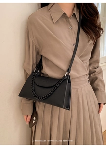 Close-up of black lychee texture crossbody bag with thick chain and leather strap