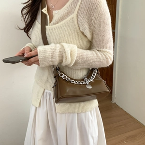 Detail of coffee leather crescent bag with bold silver chain and round metal tag