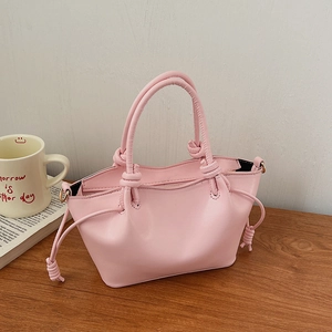 Detail of pink leather handbag with unique knotted handle and metal D-ring buckle