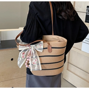 Détail du sac cabas en paille à rayures avec nœud en dentelle florale et perles