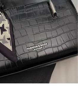 Detail of black crocodile texture bag with decorative houndstooth silk scarf on handle