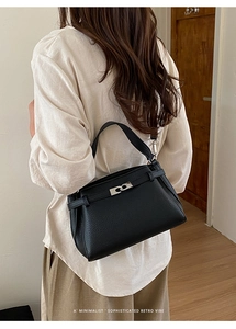 Detail view of black lychee grain leather handbag with silver metallic clasp on model