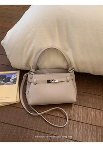 Detail of lychee pattern leather handbag with metallic lock on wooden floor