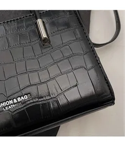 Close-up of black stone texture leather handbag with metallic silver logo lettering detail