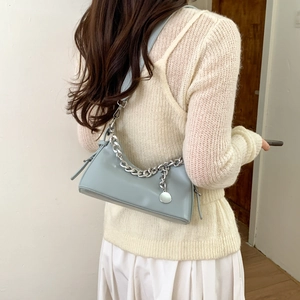 Detail of blue leather shoulder bag with chunky silver chain and round metal pendant