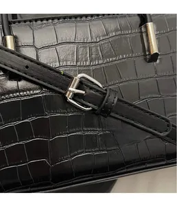 Detail shot of black crocodile texture bag with silver buckle and adjustable strap