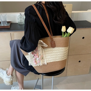 Détail d'un sac cabas en paille avec broderie en dentelle et breloque papillon rose