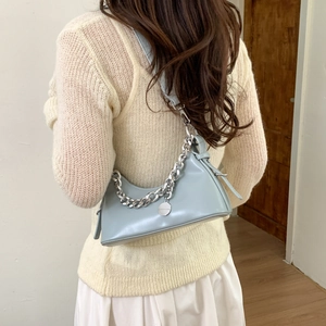 Close-up of light blue underarm bag with silver chain strap and matte PU leather detail