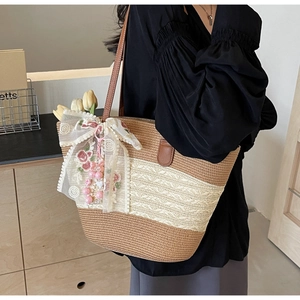 Détail du sac cabas en paille avec broderie de fleurs en dentelle et nœud ruban