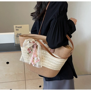 Détail du sac en paille avec dentelle blanche, broderie rose et breloque en perles roses