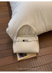 Detailed macro view of beige lychee grain leather texture with silver metal turn-lock closure