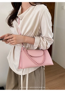 Pink lychee texture handbag with decorative chain and adjustable strap on a model