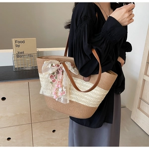 Détail du sac cabas en paille avec dentelle blanche, broderie florale et breloque rose