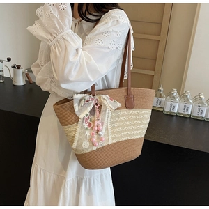 Détail du sac cabas en paille avec nœud en dentelle, broderie florale et anses en cuir