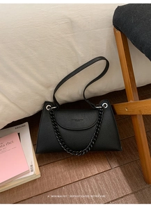 Detail of black textured leather shoulder bag with decorative thick chain and fine branding