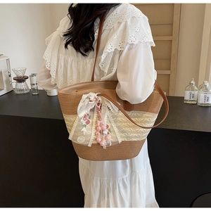 Détail du cabas en paille tressée avec ruban en dentelle, broderie florale et cuir