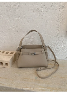 Close-up of khaki litchi grain leather bag with metal buckle and thin shoulder strap
